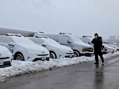 An officer from the New York Police Department (NYPD) walks by a row of police vehicles buried in snow near the Hudson Yards precinct in Manhattan, New York City 