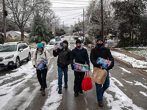 People walk back to their homes after buying packs of bottled water and other items from a convenience store in Austin, Texas 