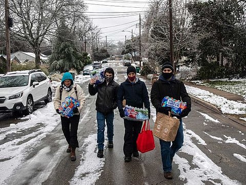 People walk back to their homes after buying packs of bottled water and other items from a convenience store in Austin, Texas 