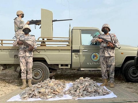 Saudi border guards stand next to the seized haul.