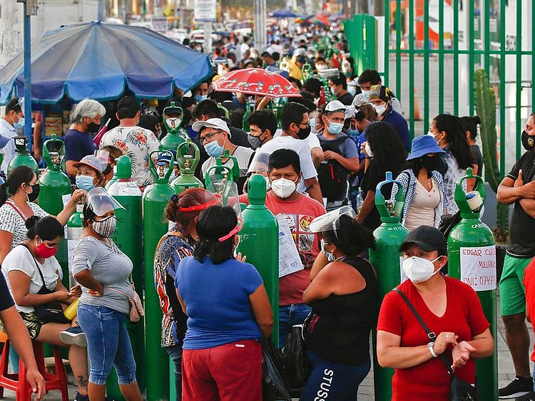 People wait to refill oxygen tanks in a queue of up to 200 people who camp outside a production plant, in San Juan de Lurigancho, Lima.  