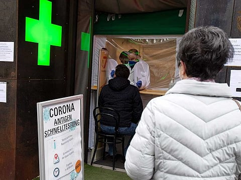 In this file photo taken on February 8, 2021 people wait in front of a pharmacy in the well-known shopping street Mariahilferstrasse in Vienna for a free antigen quick test. 