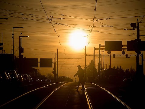 A man wearing a face mask crosses a street in Prague on a sunny day, amid the COVID-19 pandemic.