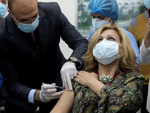 Lebanon's caretaker health minister Hamad Hasan administers a dose of the Pfizer/BioNTech vaccine against the coronavirus disease (COVID-19) to a woman, at Rafik Hariri University Hospital, in Beirut, Lebanon February 14, 2021. 