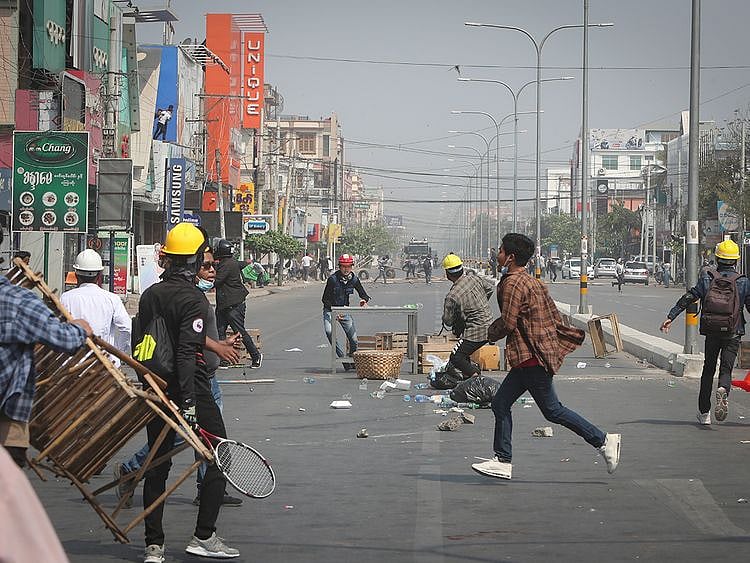 Protesters rush to try to block the road as police arrive during a protest against the military coup in Mandalay, Myanmar, on Sunday. 