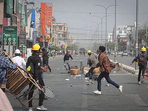 Protesters rush to try to block the road as police arrive during a protest against the military coup in Mandalay, Myanmar, on Sunday. 