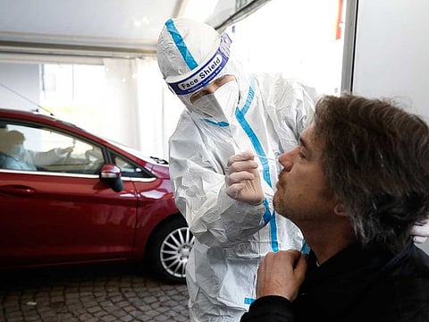 A German help worker tests for COVID-19 a French national going to Germany at the German-French border near Saarbrucken, Tuesday, March 2, 2021. 