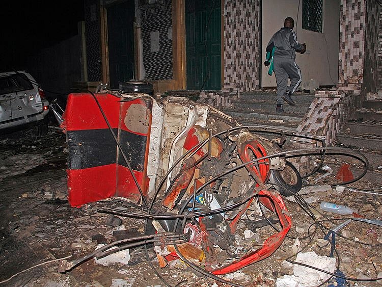 A man walks past a destroyed vehicle at the scene of a blast at a popular restaurant in the capital Mogadishu. 