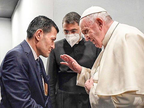 Pope Francis is seen raising his hand as if offering a blessing while looking intently at Abdullah.