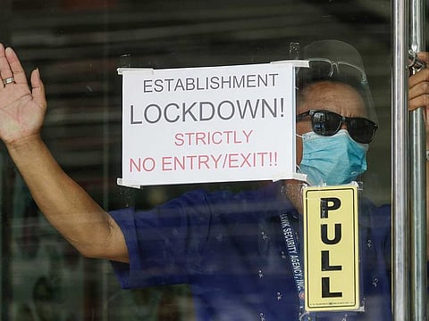 A security guard stands beside a sign at the Malate Bayview Mansion that was placed under lockdown due to the number of COVID-19 cases in Manila, Philippines on Thursday, March 11, 2021. 