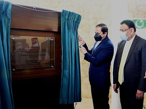 Sindh Law and Environment Adviser Barrister Murtaza Wahab unveils a plaque following the launch of the solar power project at the University of Karachi.