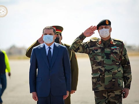Libya's Prime Minister Abdulhamid Dbeibeh stands next to military personnel as he is welcomed upon his arrival in Tripoli, Libya March 11, 2021. 
