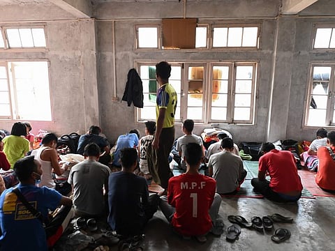Myanmarese policemen, who fled Myanmar and crossed illegally to India, sit in a temporary shelter at an undisclosed location in India's northeastern state of Mizoram on March 13, 2021. 