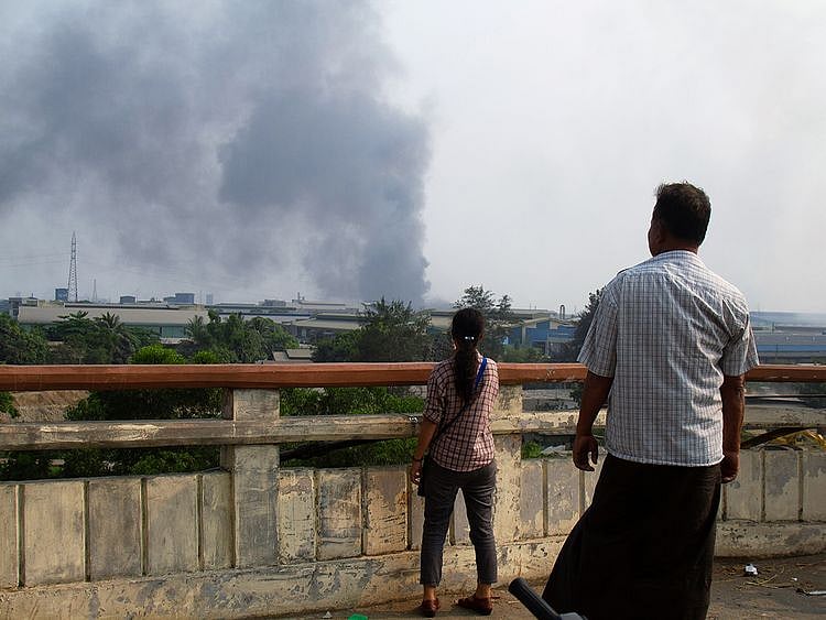 People look at smoke believed to be from a factory fire during the security force crack down on anti-coup protesters at Hlaingthaya, Yangon.