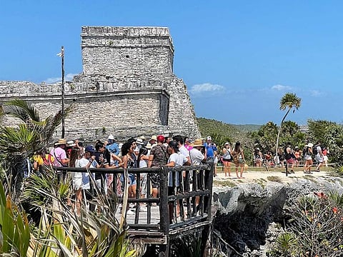 Tourists enjoy the Pre-Columbian Mayan site of Tulum, built on the eastern coast of the Yucatan Peninsula on the Caribbean Sea, in the Mexican state of Quintana Roo