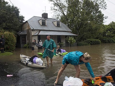 Residents unload household items from kayaks at a street submerged in floodwaters in Windsor, New South Wales, Australia, on Monday, March 22, 2021.