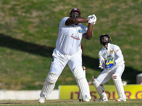 Rahkeem Cornwall (L) of West Indies hits a six as Niroshan Dickwella (R) of Sri Lanka watches.