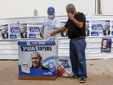A party member distributes campaign materials for Benjamin Netanyahu, Israel's prime minister and the leader of the Likud party, outside a polling station in Be'er Sheva, Israel, on Tuesday, March 23, 2021. 