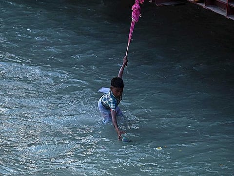 A boy catches offerings thrown by Hindu devotees in Ganges river after performing religious rituals during the ongoing Kumbh Mela festival in Haridwar on March 12, 2021. Dozens of coin pickers eke out a living retrieving offerings thrown into India's sacred Ganges river by pilgrims visiting the holy city of Haridwar in the northern state of Uttarakhand. 
