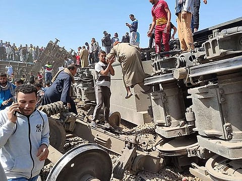 People gather around the wreckage of two trains that collided in the Tahta district of Sohag province, some 460 kms south of the Egyptian capital Cairo, reportedly killing at least 32 people and injuring scores of others, on March 26, 2021. 