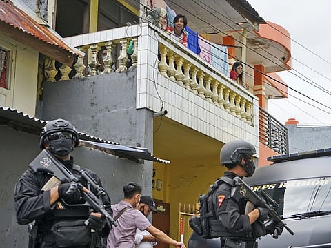 Residents look on as police officers stand guard during a raid on the house of the the suspected suicide bombers in Sunday’s church attack, in Makassar, South Sulawesi, Indonesia, Monday, March 29, 2021. 