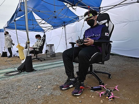 Kang Chang-hyeon (R), a teenaged drone-racing champion, using a controller and virtual-reality goggles to pilot his aircraft during a drone-racing league round in the southern county of Hadong.