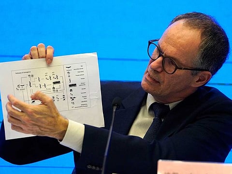 In this Feb. 9, 2021, file photo, Peter Ben Embarek of the World Health Organisation team holds up a chart showing pathways of transmission of the virus during a joint news conference at the end of the WHO mission in Wuhan in central China's Hubei province. A joint WHO-China study on the origins of COVID-19 says that transmission of the virus from bats to humans through another animal is the most likely scenario. 