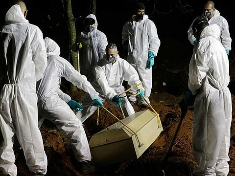Cemetery workers lower the coffin of a COVID-19 victim into his grave at the Vila Formosa cemetery in Sao Paulo, Brazil, late Wednesday, March 31, 2021. 