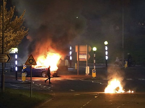 A man walks past a burning car that was hijacked by Loyalists at the Cloughfern roundabout in Newtownabbey. Masked men threw petrol bombs and hijacked cars in the Loyalist area North of Belfast.