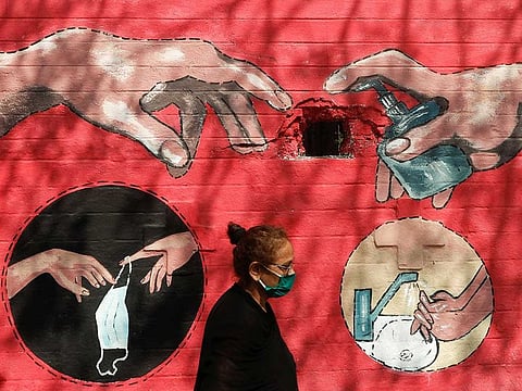 A woman walks past a graffiti, on a street, amidst the spread of the coronavirus disease (COVID-19) in Mumbai, India, April 6, 2021. 