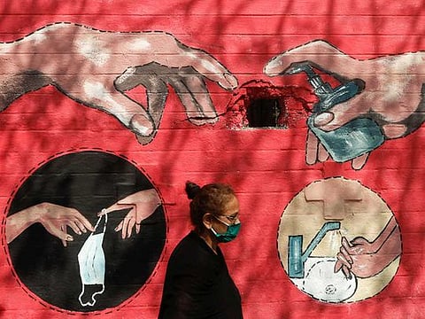 A woman walks past a graffiti, on a street, amidst the spread of the coronavirus disease (COVID-19) in Mumbai, India, April 6, 2021. 
