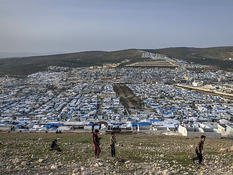 Children play on a hillside above a sprawling refugee camp in the village of Qah in northwestern Syria on March 22, 2021. Millions of people displaced during Syria’s 10-year war are impoverished, insecure and crowded into an area of the country’s northwest controlled by militant groups.