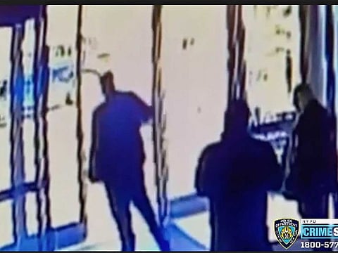 This image taken from surveillance video provided by the New York City Police Department shows an apartment building employee, centre, closing the building's front door after a man assaulted a 65-year-old Asian American woman, Monday afternoon, March 29, 2021, a few blocks from New York's Times Square. 