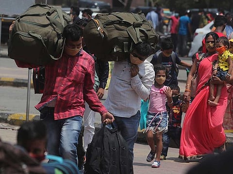 Passengers wearing face masks carry their luggage at Lokmanya Tilak Terminus to catch trains in Mumbai, India. Wednesday, April 7, 2021. 