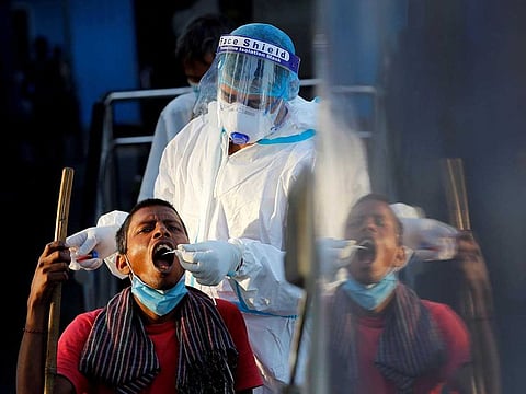 A healthcare worker collects a coronavirus disease (COVID-19) test swab sample from a man in New Delhi.