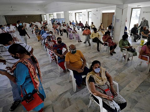 People sit in a waiting area to receive a dose of COVISHIELD at a vaccination centre in Ahmedabad, India