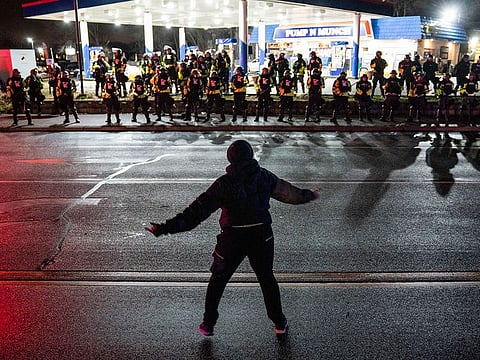A demonstrator heckles authorities who advanced into a gas station after issuing orders for crowds to disperse during a protest against the police shooting of Daunte Wright, late Monday, April 12, 2021, in Brooklyn Center, Minn. 