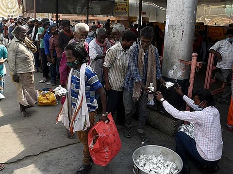 A man distributes food packets to needy people amid the surge in COVID-19 cases, in Patna on Wednesday, April 14, 2021. 