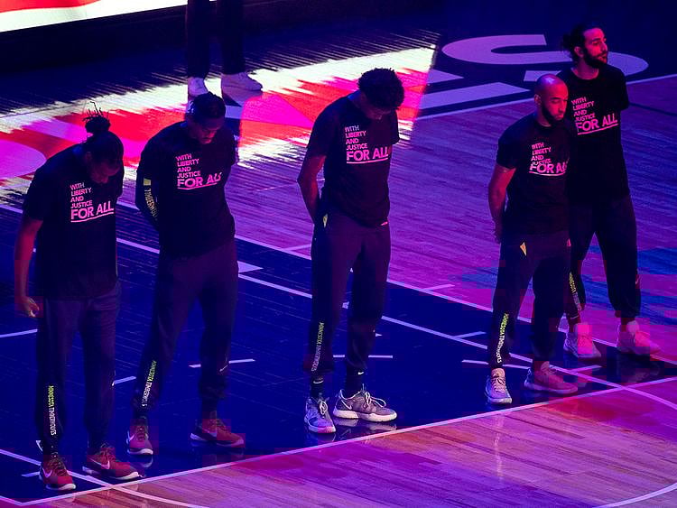 Members of the Minnesota Timberwolves, pictured, and the Brooklyn Nets wear T-shirts that read "With liberty and justice for all" as a tribute to Daunte Wright, before an NBA basketball game Tuesday, April 13, 2021, in Minneapolis. Wright was fatally shot during a traffic stop in Brooklyn Center, Minn. (AP Photo/Craig Lassig)