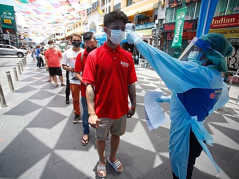 A health worker checks the temperature of a man standing in line for a COVID-19 swab test in Khaosan Road in Bangkok, Thailand Wednesday, April 14, 2021.