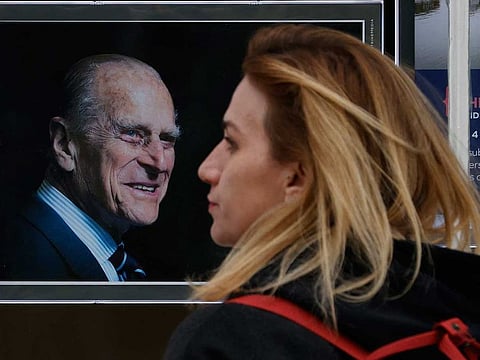 A pedestrian walks past a picture of Britain's Prince Philip, Duke of Edinburgh displayed in the window of an estate agency in Windsor, west of London, on April 16, 2021, following the April 9 death of Britain's Prince Philip, Duke of Edinburgh, at the age of 99. Final preparations continued Friday in Britain for the funeral of Queen Elizabeth's husband Prince Philip on Saturday. 
