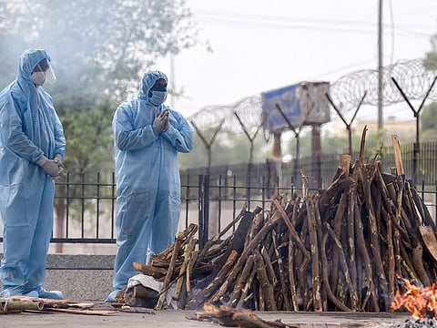 Family members pray during cremation of a person who died of COVID-19 at the Seemapuri Cremation Grounds, in New Delhi, on Friday, April 16, 2021. 