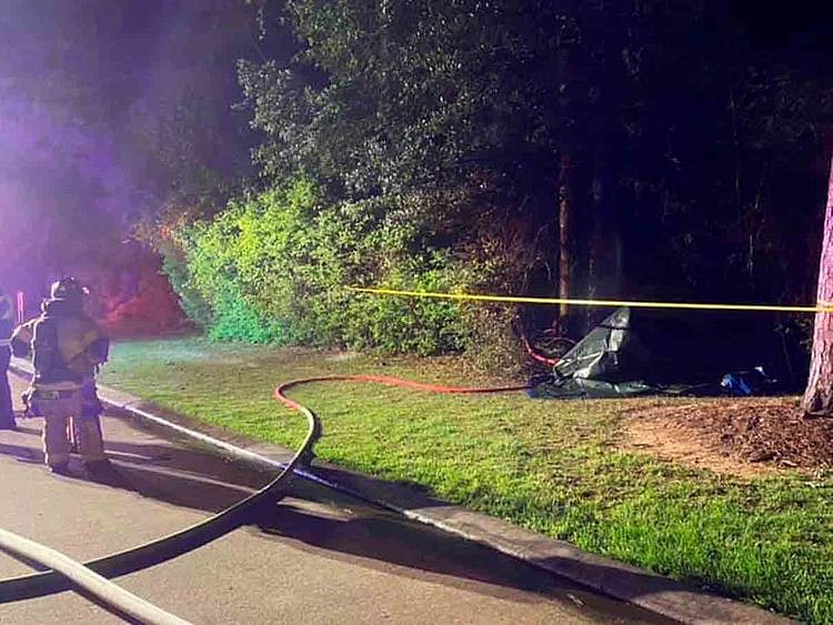 A fireman looks on near a Tesla vehicle, which is covered in tarp, after it crashed in The Woodlands, Texas, April 17, 2021, in this image obtained via social media