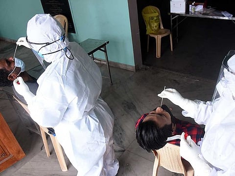 Health workers in PPE kits collect nasal samples from people for the COVID-19 test, in Kochi on Monday, April 19, 2021. 