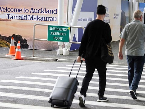 A traveller crosses a road at Auckland International Airport in Auckland, New Zealand, on Monday, April 19, 2021.