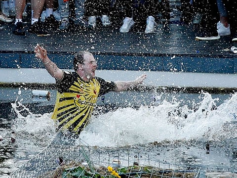 A Watford fan jumps into a fountain after his club sealed promotion to the Premier League 