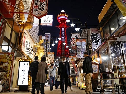 Pedestrians wearing protective face masks, amid the coronavirus disease pandemic, are seen in front of the Tsutenkaku Tower in Osaka, Japan.