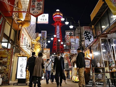 Pedestrians wearing protective face masks, amid the coronavirus disease pandemic, are seen in front of the Tsutenkaku Tower in Osaka, Japan.