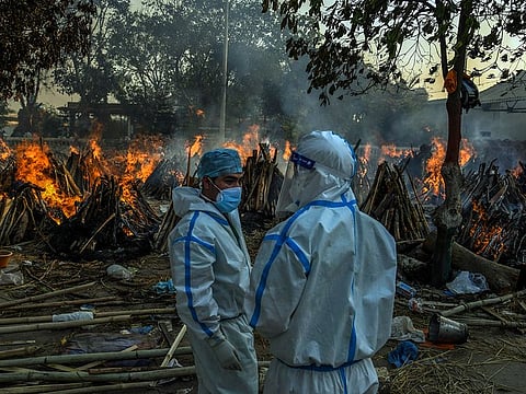 Relatives stand in front of funeral pyres of those who died from the coronavirus, at a crematorium in New Delhi on April 26, 2021.  