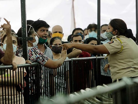 A man argues with a policewoman as he waits with others to receive COVID-19 vaccine outside a vaccination centre in Mumbai, India